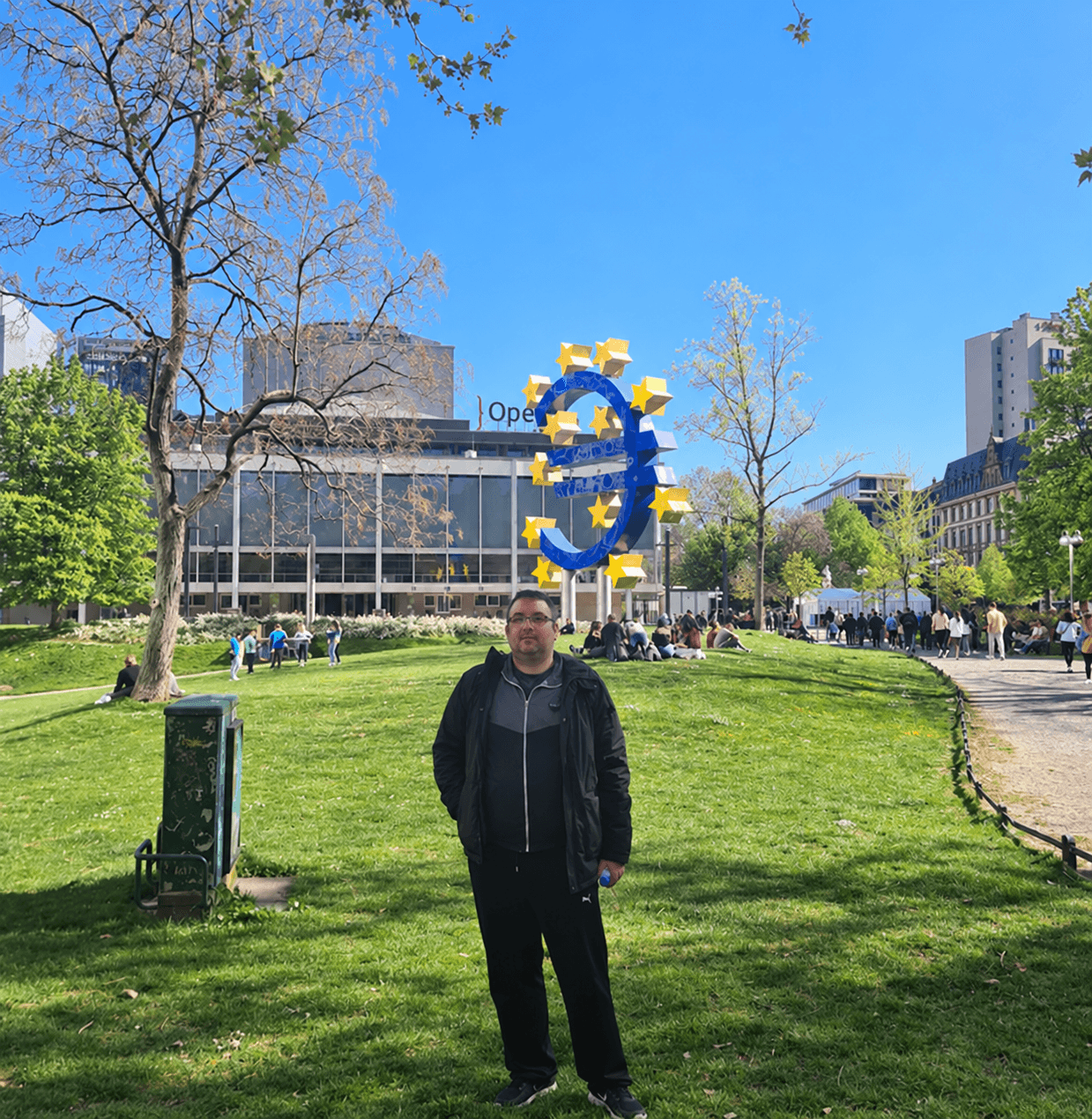 Danilo Vučković stoji na zelenoj površini u Frankfurtu, u blizini velike plave skulpture eura.